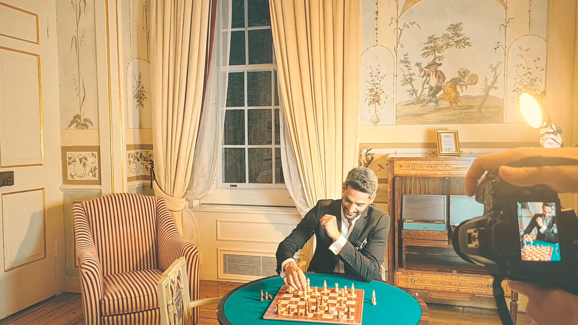 Gentleman’s Club — video still of a man playing chess in a period room, with camera in frame