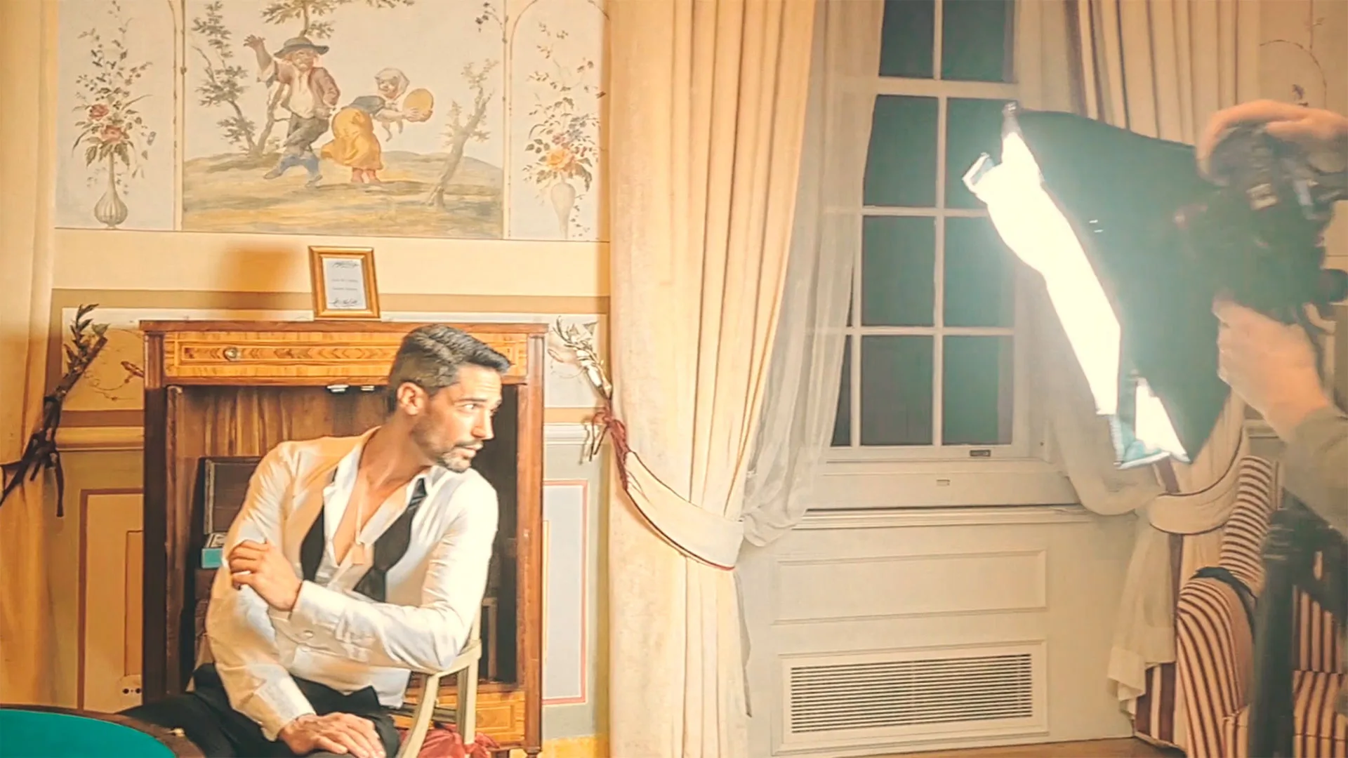 Gentleman’s Club — behind-the-scenes still of a man posing in a white shirt under studio lighting