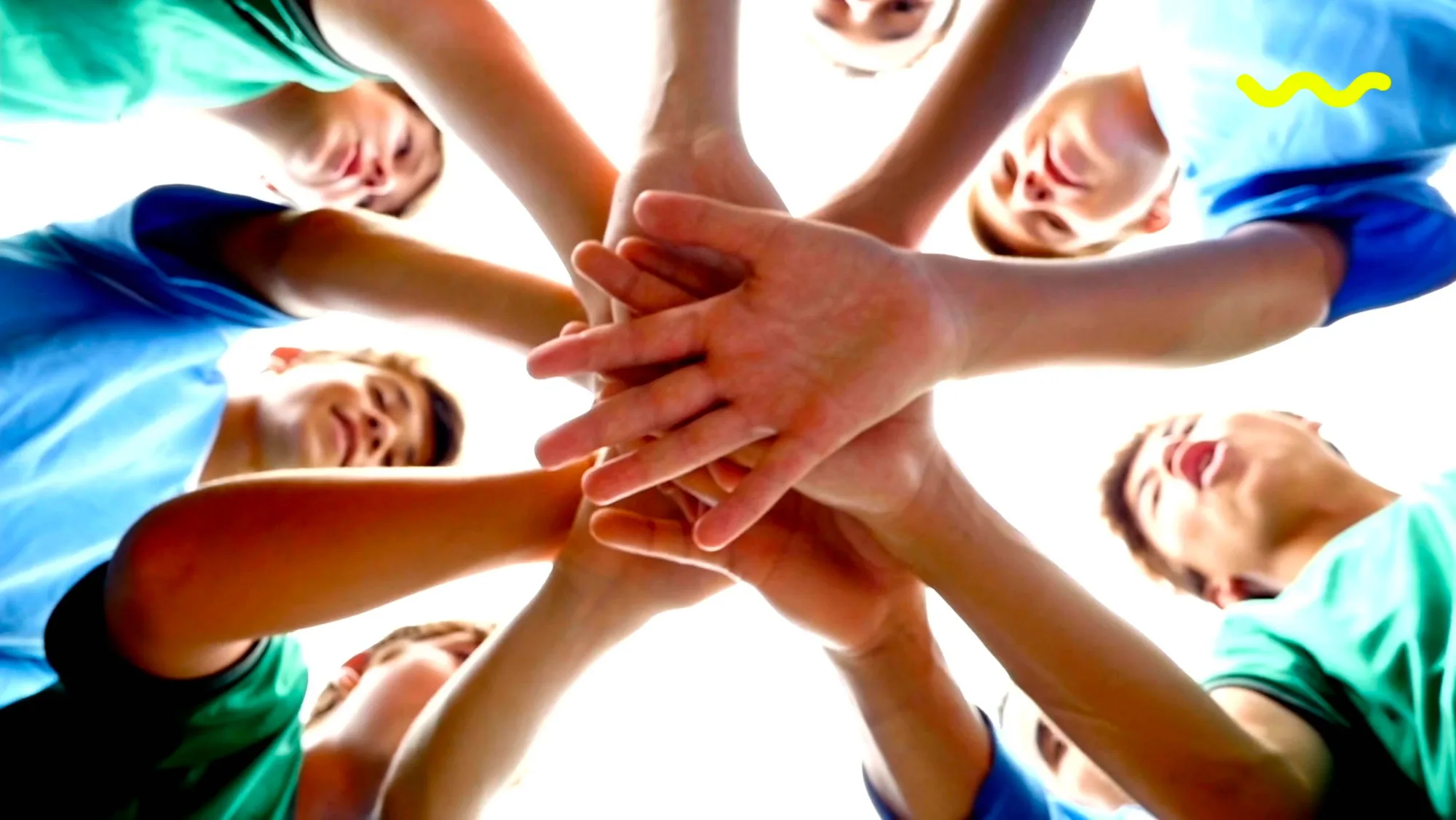 Tetrapak Sempre no Amarelo — low-angle video still of young people stacking hands in a huddle